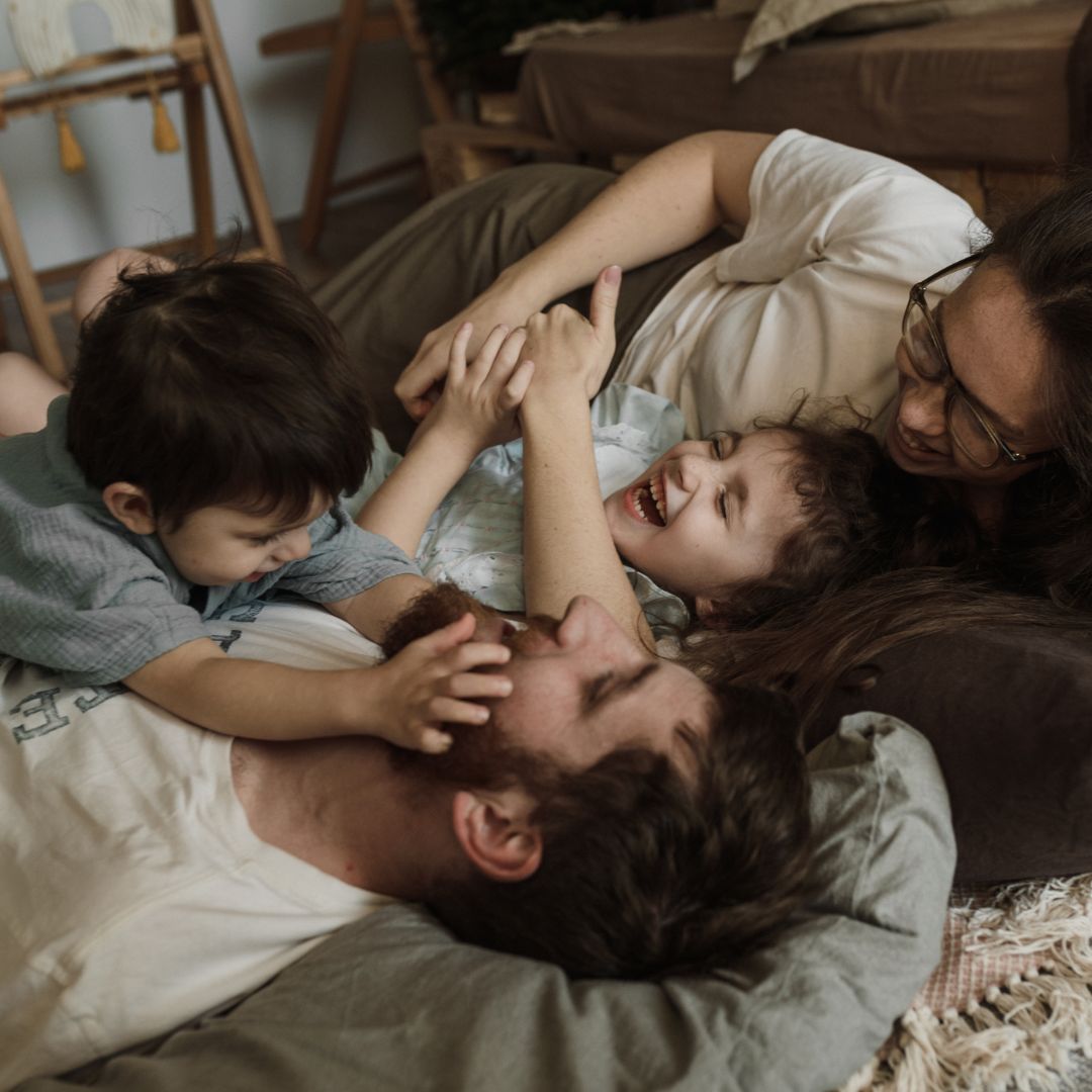 smiling family cuddling in bed